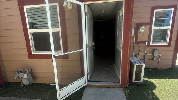 Un edificio residencial con la puerta principal abierta, mostrando un interior oscuro.