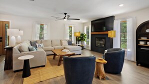 Una sala de estar moderna con un sofá, una mesa de centro, sillas, una chimenea y un televisor.