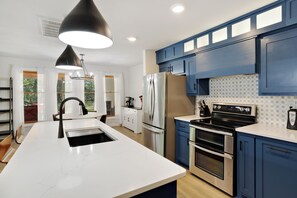 A modern kitchen with a marble countertop, stainless steel appliances, and blue cabinetry.