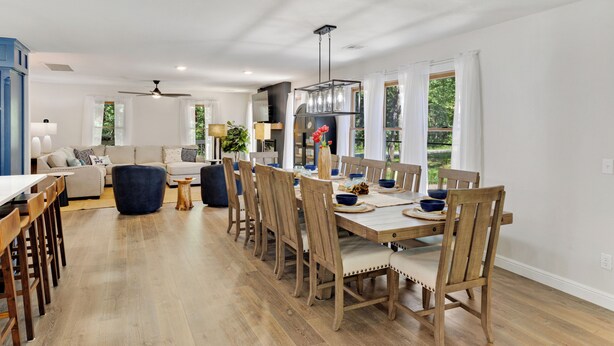 Un comedor con una mesa de madera, sillas y una cocina moderna al fondo.