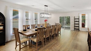 Un comedor con una larga mesa de madera, sillas y una lámpara colgante.