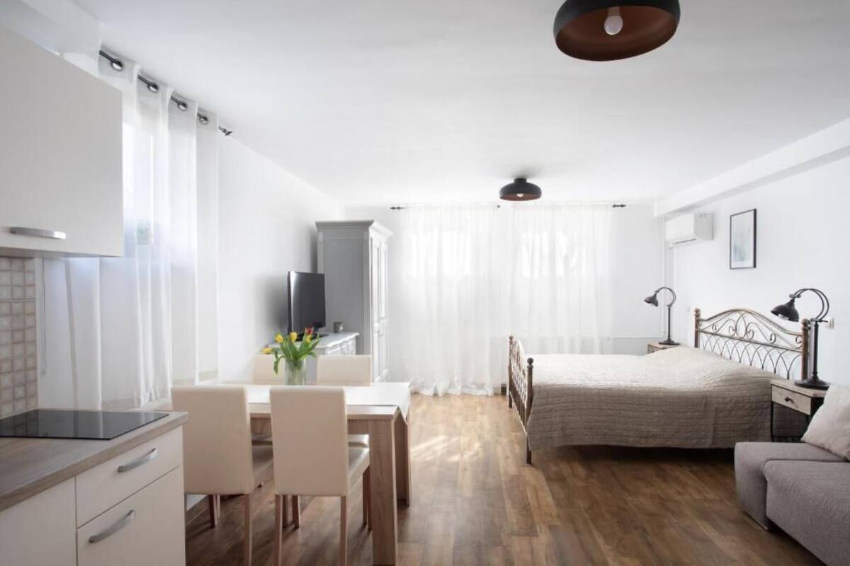 A modern, well-lit room with a bed, a desk, and a dining area.