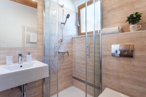 A modern bathroom with a glass-enclosed shower, a sink with two faucets, and a towel rack. - Holiday lake Bled (Bled)