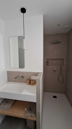 Une salle de bain moderne avec un lavabo blanc, un miroir et une douche.