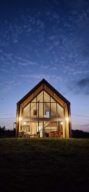 Una casa moderna con ventanas amplias y techo inclinado, rodeada de un césped.