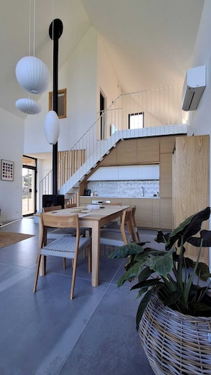 Una cocina moderna con una mesa y sillas de madera, una escalera y una planta grande.