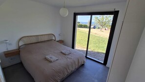 Une chambre à coucher avec un lit, une table de chevet, une lampe et une vue sur l’extérieur.