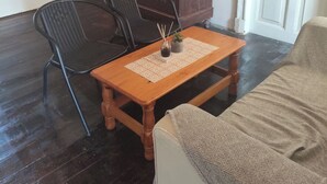 Una habitación con una mesa de madera, dos sillas, un sofá, un aparador de madera oscura y una puerta blanca.
