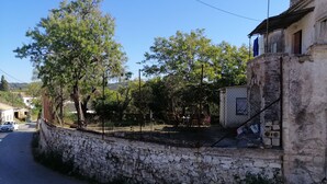 Un muro de piedra, un edificio con balcón y cielo despejado.
