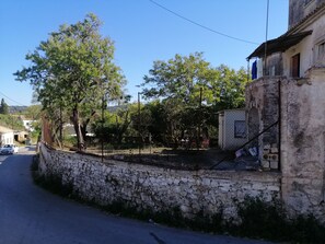 A stone wall, a building with a balcony, and a clear sky. - Belvedere di Van D'oro 1886 (Peroulades)