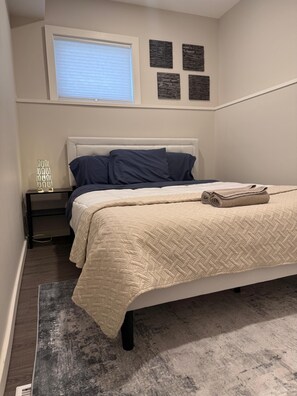 Ein Schlafzimmer mit Bett, Nachttisch, Fenster und Wandbildern.
