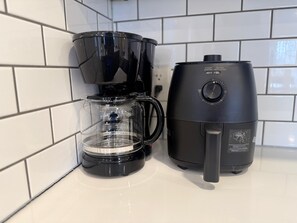 Eine schwarze Kaffeemaschine und eine Glaskaraffe auf einer weißen Fliesenarbeitsplatte.