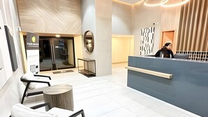 A modern reception area with a desk, chairs, and a glass door entrance. - Depto. cerca Movistar Arena con WIFI (Santiago)