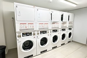 Un cuarto de lavandería con varias lavadoras y secadoras, numeradas para su identificación.