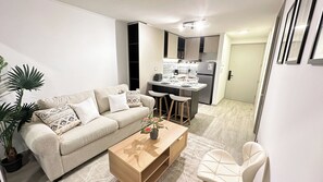 Un espacio habitable pequeño con sofá, mesa de centro y una zona de cocina.