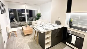 A modern kitchen with a dining area, a built-in oven, and a large window overlooking a balcony. - Depto. cerca Movistar Arena con WIFI (Santiago)