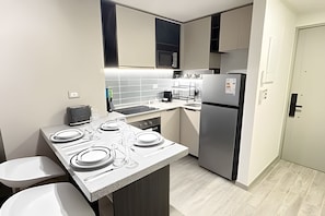 Una cocina compacta con microondas, refrigerador y una pequeña isla con pileta.