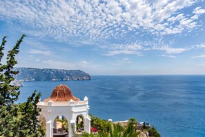 A coastal view with a white building featuring a red-tiled dome, overlooking the sea and a distant island. - Villa rental in Cumbre del Sol DIVINA (Benitachell)
