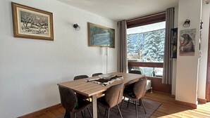 A dining area with a wooden table, six chairs, a rug, and two framed artworks on the wall. - Pragelato Weekend (pragelato)