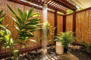 Uma cerca de bambu com um elemento de água e plantas em vasos.