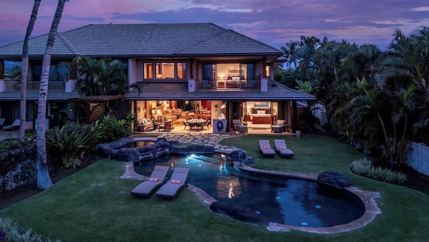 A two-story house with a swimming pool, outdoor seating, and lush landscaping. - One Ocean Estates by KBM (Waikoloa)