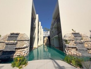 A swimming pool with stone walls and a clear sky. - Modern Swim-Up Studio by the Pool - Mizu 20 (Tulum)