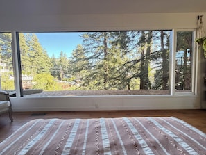 Una habitación con un ventanal grande, una cama con una manta a rayas y suelo de madera.