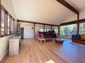 A spacious living area with a large window, wooden beams, a sofa, and a coffee table.
