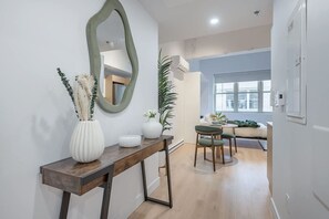 Ein modernes Interieur mit einem Holzkonsolentisch, einem Spiegel und einem Essbereich mit einem grünen Stuhl.