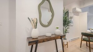 Ein modernes Wohnzimmer mit einem Holzkonsolentisch, einem grünen Spiegel und einem Topfpflanzen.