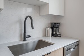 Eine Küche mit modernem Wasserhahn, einer Kaffeemaschine und einem Geschirrspüler.