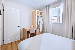 Une chambre à coucher comprenant un lit, un bureau, une chaise, une armoire et une fenêtre avec des rideaux.