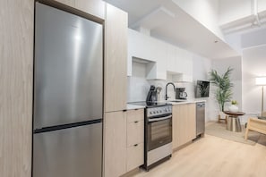 Eine moderne Küche mit Edelstahlgeräten, hellem Holzkorpus und einer zentralen Kochinsel.