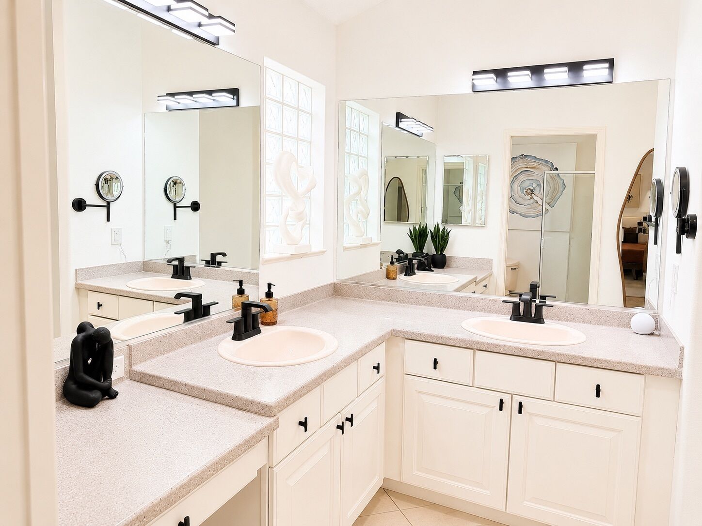 A modern bathroom with two sinks, large mirrors, and built-in cabinets.