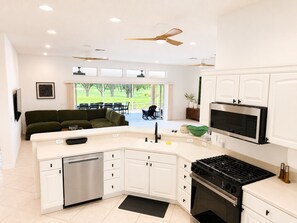 A modern kitchen with white cabinetry, a built-in oven, a stove, and a dishwasher. - Golf Course Retreat in The Villages with Water Views, Lanai & Prime Location (Lady Lake)