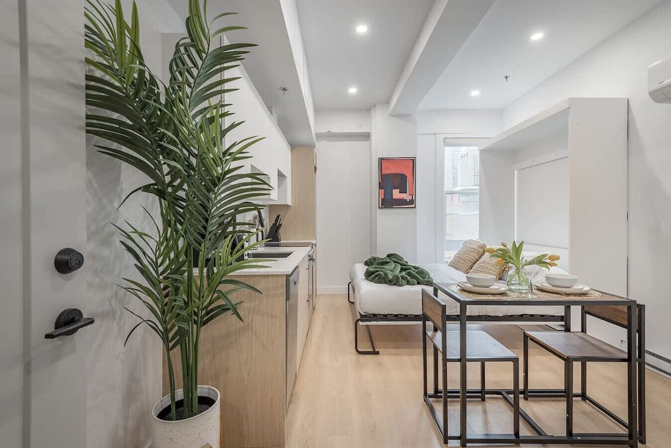 Une cuisine moderne avec un coin repas, un lit et une grande plante en pot.