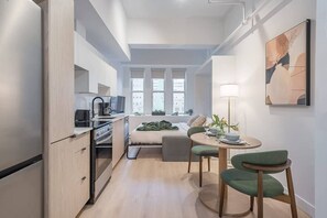 A compact living space with a kitchenette, a dining area, and a sofa bed.