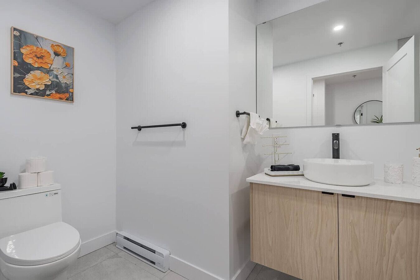 Une salle de bain moderne équipée de toilettes, d’un lavabo, d’un miroir et d’une douche.