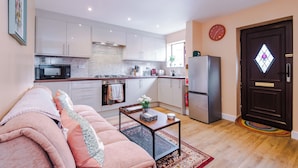Eine moderne Wohnung mit Küche, Wohnzimmer und einer Tür mit einem rautenförmigen Fenster.