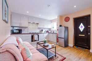 Un apartamento moderno con cocina, sala de estar y una puerta con un ventanal en forma de rombo.