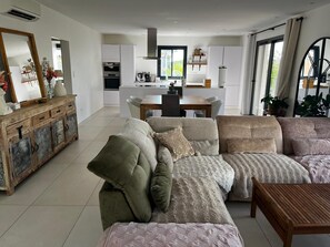 A modern living room with a sofa, a wooden coffee table, and a dining area with a table and chairs. - Romantic villa for 6 near the sea with private pool (Fréjus)