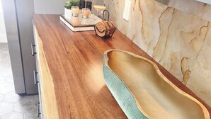 Una cocina con encimera de madera, salpicadero de mármol y pileta con interior verde.