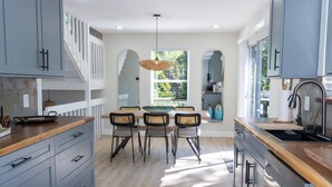 Una cocina moderna con armarios azul claro, una encimera de madera y un comedor con cuatro sillas.