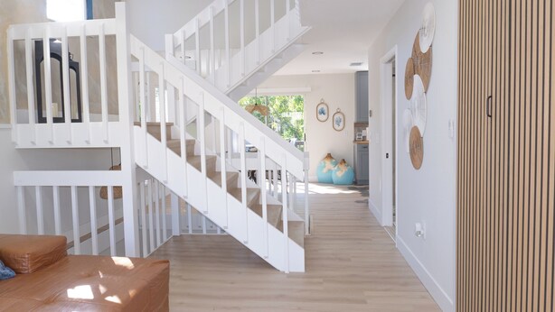 Un interior espacioso con escalera, piso de madera y vistas al exterior.