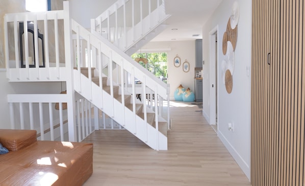 A spacious interior with a staircase, wooden flooring, and a view to the outdoors.