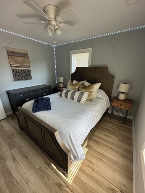 A bedroom with a bed, nightstands, a ceiling fan, and LED strip lighting. - Queens place, sleeps 12 (Raleigh)