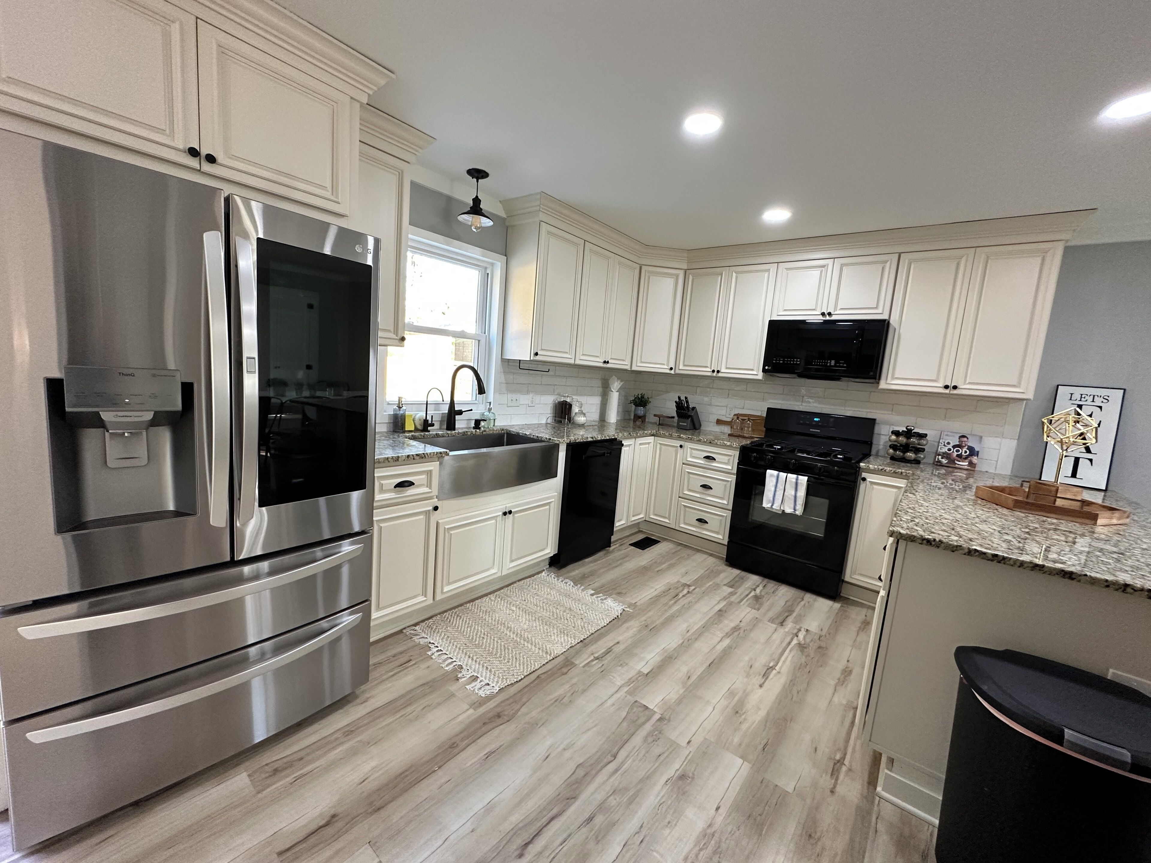 A kitchen with stainless steel appliances, white cabinetry, a granite countertop, and a wooden floor.. Queens place, sleeps 12