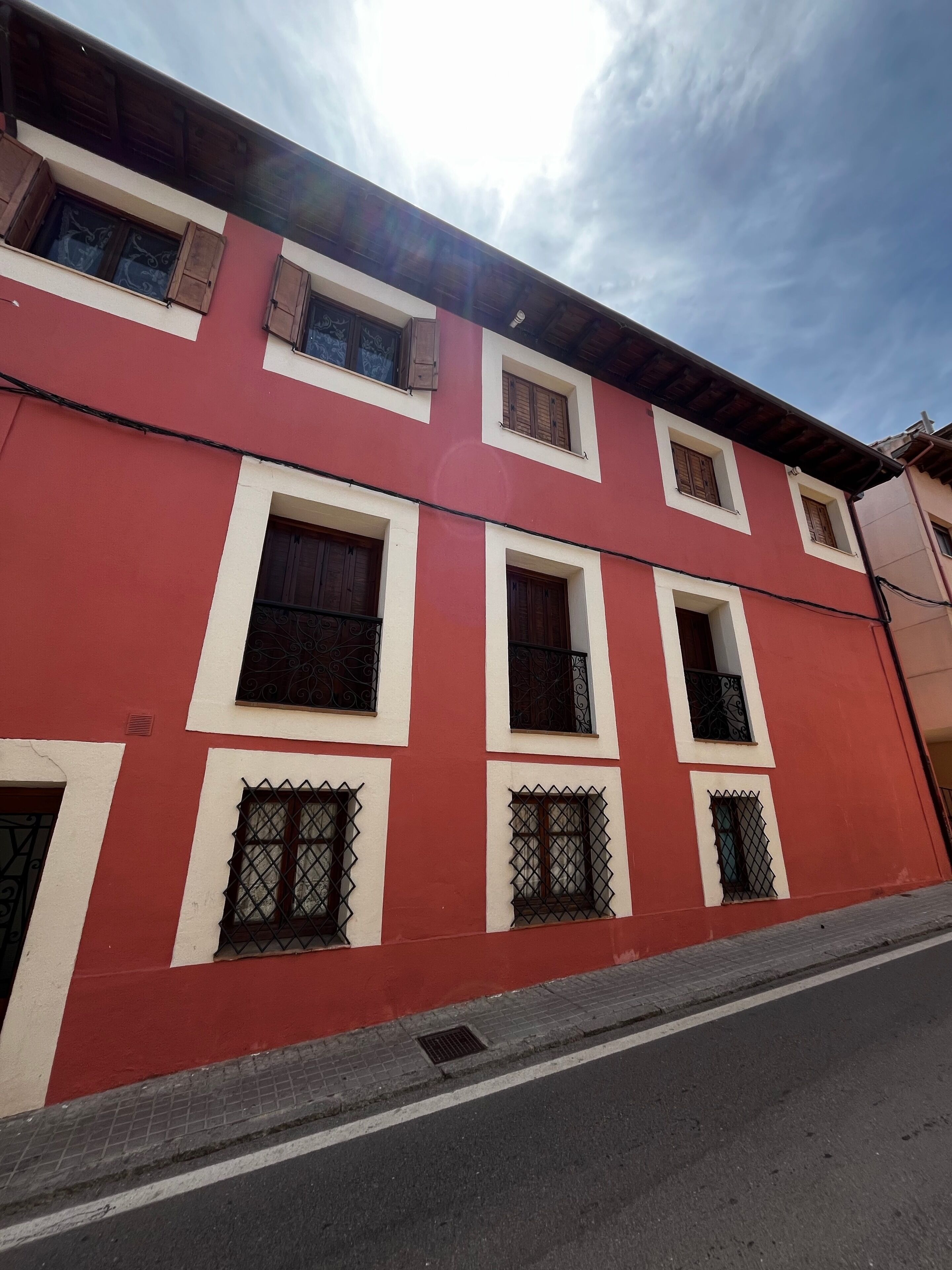 Un edificio rojo con varias ventanas y un cielo despejado.