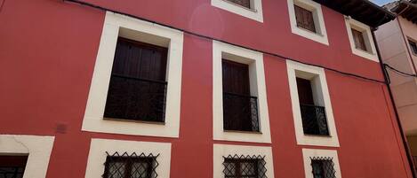 Un edificio rojo con varias ventanas y un cielo despejado.