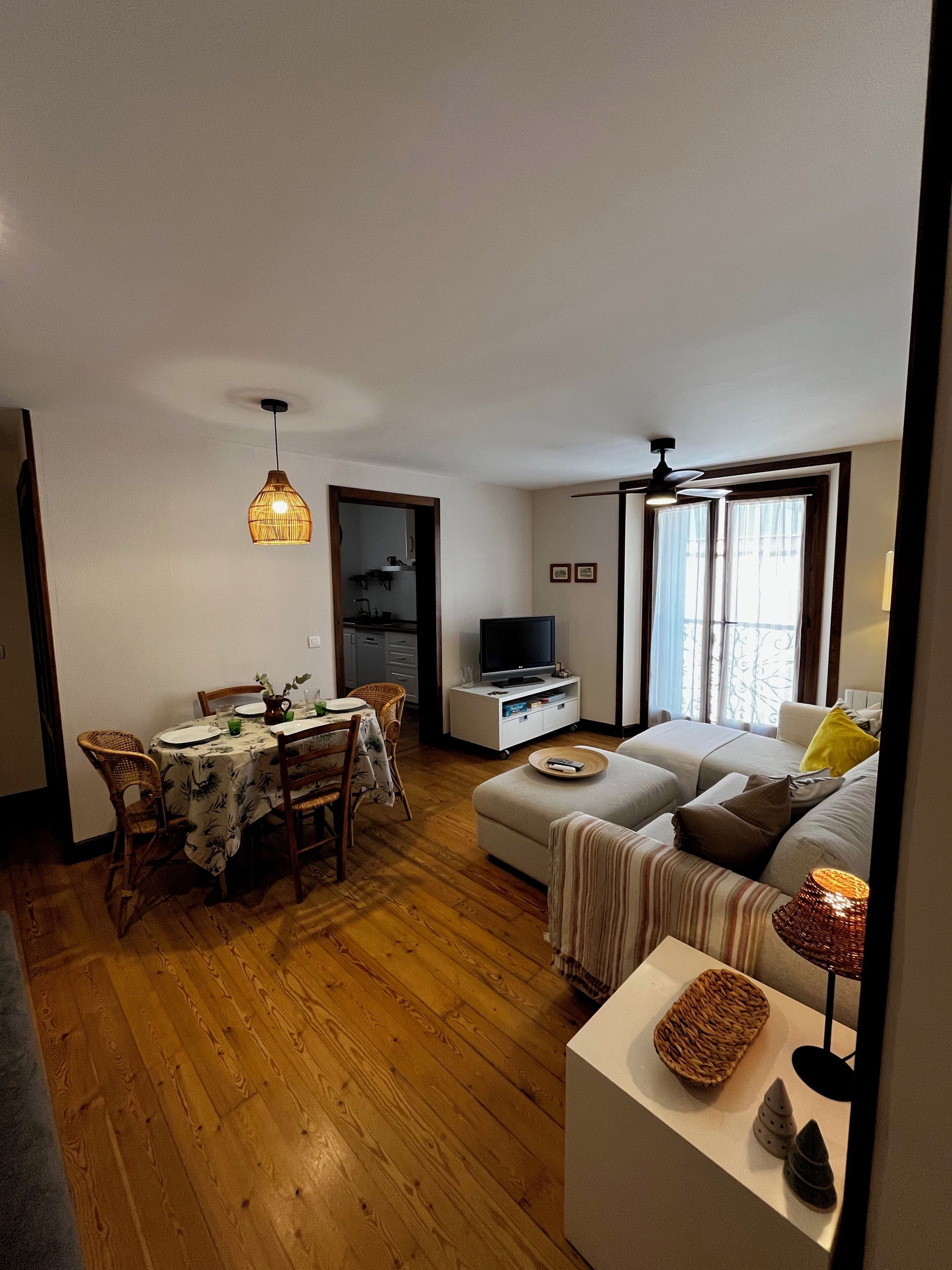 Un salon comprenant un coin repas, un plancher en bois, un téléviseur et un canapé.